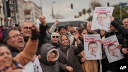 Supporters of Istanbul Mayor Ekrem Imamoglu hold up his pictures outside a police station after his arrest