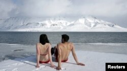 Activiștii ecologiști Lesley Butler and Rob Bell „se bronzează” pe malul unui fiord arctic, din apropierea orașului norvegian Longyearbyen