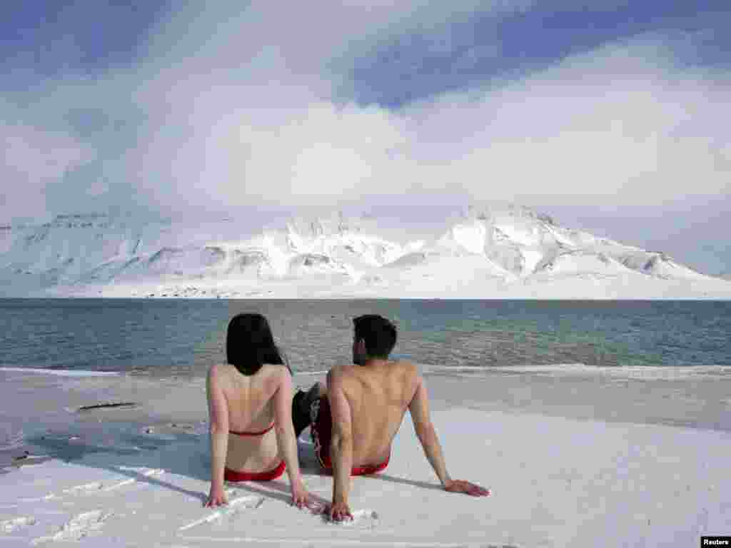 Climate activists Lesley Butler and Rob Bell (R) "sunbathe" on the edge of a frozen fjord in the Norwegian Arctic town of Longyearbyen April 25, 2007. The activists are warning that global warming could thaw the Arctic and make the sea warm enough for people to swim and sunbathe in. REUTERS/Francois Lenoir 