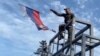 A Ukrainian soldier takes down a Russian flag hoisted on a monument in Lyman on October 1.