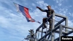 A Ukrainian soldier takes down a Russian flag hoisted on a monument in Lyman on October 1.