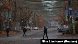 Люди переходять вулицю, накриту антидроновою сіткою у прифронтовому місті Херсон, Україна, 11 листопада 2025 року