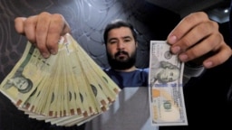 A money changer poses for the camera with a $100 bill and the a wad of Iranian currency to show loss of value. File photo