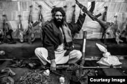 "Талибан" мүшесі қаруларын көрсетіп отыр.