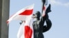 BELARUS – A man attaches an old Belarusian national flag to a statue of the memorial of the WWII opposition rally in the center of Minsk, August 16, 2020