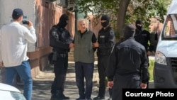 Белсенді Мұратбай Жұмағалиеве ұқсас адамды қара киген арнайы жасақ өкілдері ұстап тұр. 3 маусым 2026 жыл. Белсендінің туыстары жіберген сурет.