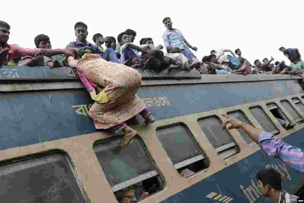 A woman tries to climb on the rooftop of an overcrowded train in an attempt to travel to her village, ahead of the Eid al-Adha celebrations, at the Airport Railway Station in Dhaka, Bangladesh. (epa/Abir Abdullah)