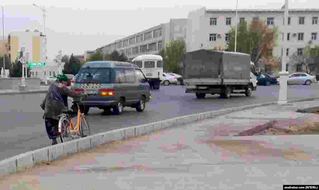 Turkmenabat. Ýol ýakasynda tigire münjek bolup duran aýal