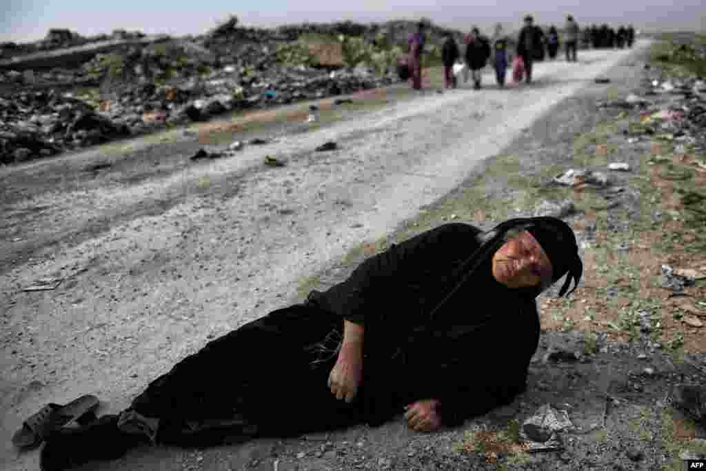 Një grua irakiane shtrihet përtokë derisa po ikte me civilët nga Mosuli.
