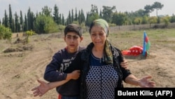 Aybeniz Khasanova, the mother of a 29-year-old soldier killed during fighting with Armenia, grieves next to his grave near the city of Agdam. Many other mothers are still awaiting word on the fates of their sons.