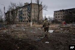 Un militar din marina ucraineană aleargă pentru a se plasa pe poziții, printre blocurile din Vuhledar, oraș aflat pe linia frontului, Ucraina, sâmbătă, 25 februarie 2023.