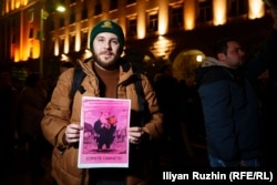 Protester Alexander Karatov holds a sign reading "Stop The Pigs."