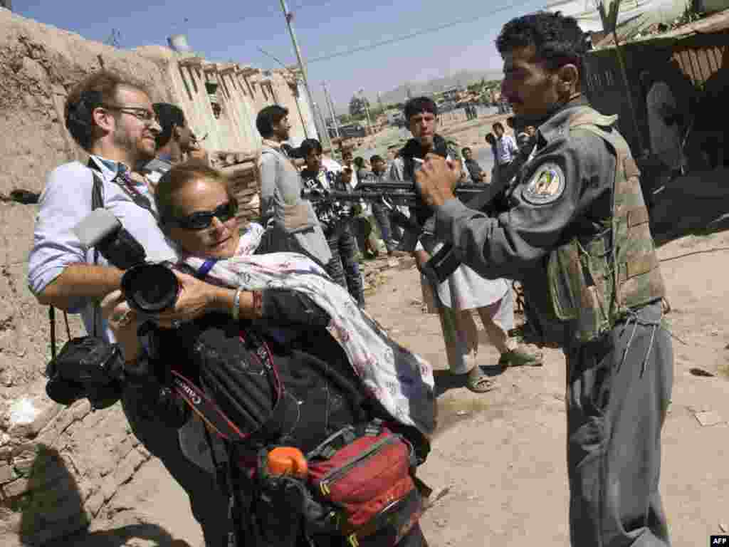 Oružjem na fotoreportere - Avganistan - Avganstanski policajac uperio je oružje na fotoreportere kako bi ih sprečio da priđu području u kojem su militanti zauzeli banku. 19. avgust 2009. 