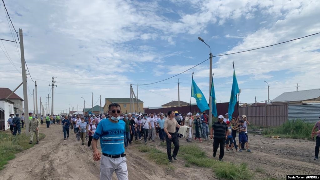 Приехавшие на поминки по Дулату Агадилу люди идут на кладбище, где он похоронен. Село Талапкер Акмолинской области, 8 августа 2020 года.