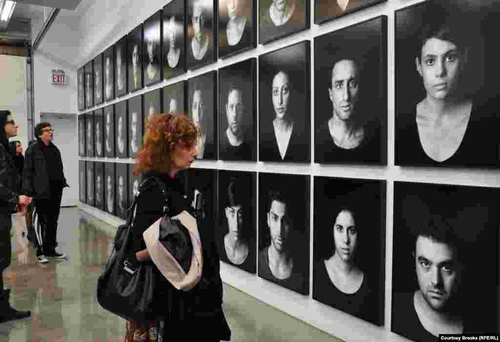 A woman surveys pictures of "The Masses," Shirin Neshat's depiction of those affected by oppression, protests, and civil unrest.