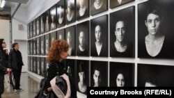 U.S. -- A woman surveys pictures of "The Masses," Iranian artist Shirin Neshat's depiction of those affected by oppression, protests, and civil unrest, New York, 12Jan2012