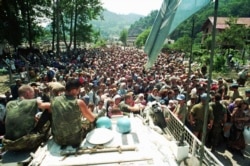 O mulțime de refugiați înconjiară un vehicul blindat al ONU în Potocari, la nord de Srebrenica, pe 13 iulie.