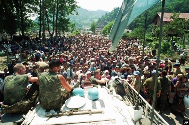 Paqeruajtësit holandezë të OKB-së, të ulur në automjetin e tyre të blinduar, përpara një turme të refugjatëve myslimanë nga Srebrenica, më 13 korrik, 1995.