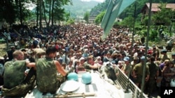 Dutch UN peacekeepers sit on top of an armored personnel carrier while Muslim refugees from Srebrenica gather in the village of Potocari, just north of Srebrenica, on July 13, 1995.