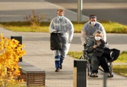 Коронавирус жұқтырған науқастарды емдейтін ауруханада мүгедек арбасына отырған әйелді тасымалдау үстінде. Көрнекі сурет.