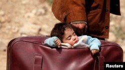 کودکی در کیف پدرش در روستای بیت ساوا در غوطه شرقی سوریه خوابیده است. ۱۵ مارس ۲۰۱۸.