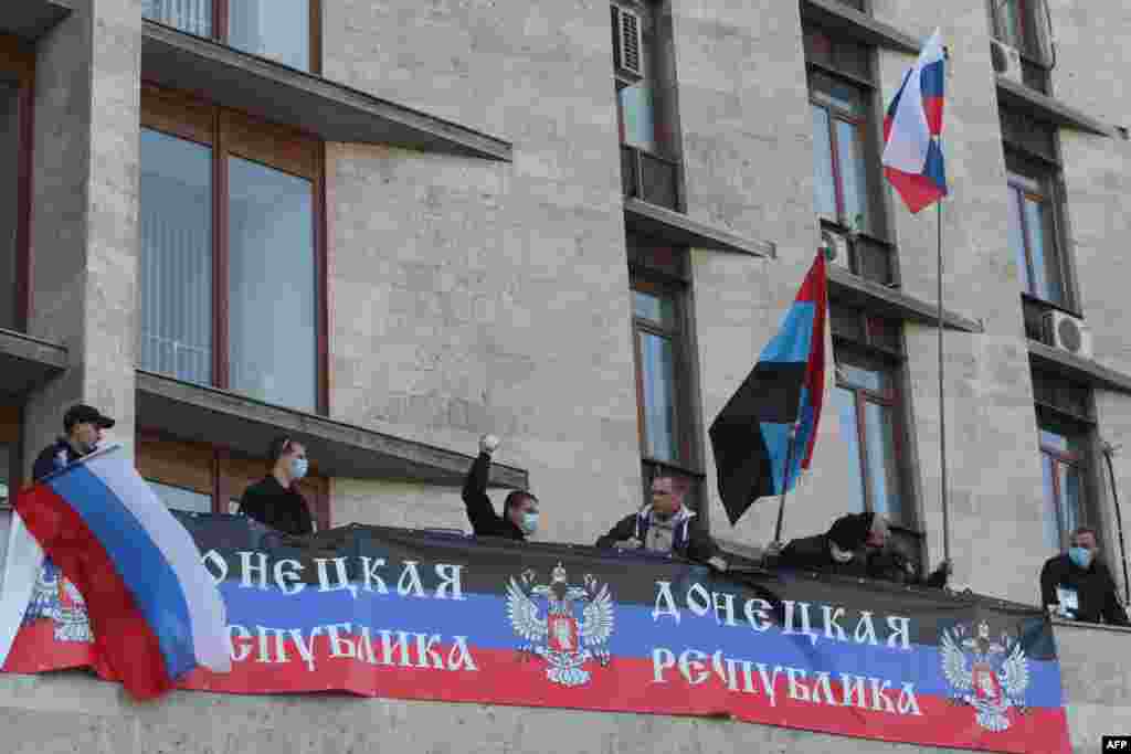 Pro-Russian supporters deploy a Russian flag and the flag of the so-called Donetsk Republic as they storm the regional administration building in Donetsk.