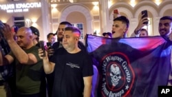 Emberek kiabálnak és integetnek a Wagner-csoport zsoldosszervezet zászlóját lengetve a katonáknak, mielőtt elhagynák a Déli Katonai Körzet székhelyét az oroszországi Rosztov-na-Donuban 2023. június 24-én