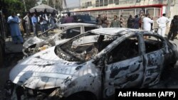 Pakistani security personnel stand next to burned-out vehicles in front of the Chinese Consulate after an attack in Karachi on November 23.