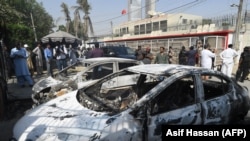 Pakistani security personnel stand next to burned-out vehicles in front of the Chinese Consulate after an attack in Karachi on November 23.