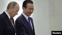Chinese Prime Minister Wen Jiabao (right) gestures next to his Russian counterpart, Vladimir Putin, during a welcome ceremony in Beijing on October 11.