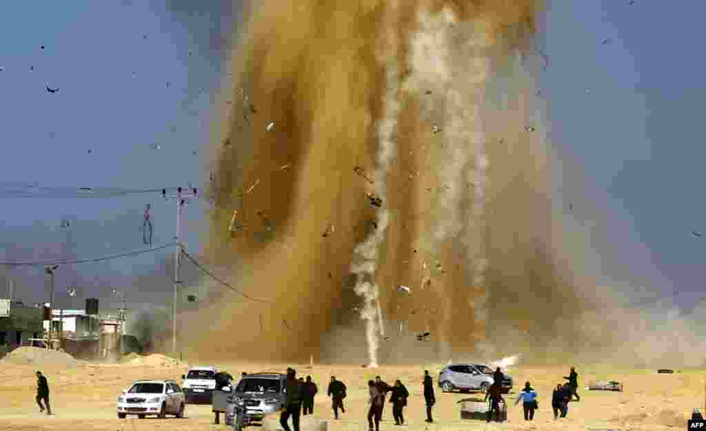 Palestinians run for cover as smoke rises following an Israeli air strike on a Hamas post in the northern Gaza Strip on February 6. (AFP/Mohammed Abed)