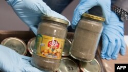 Germany -- A police officer presents seized pickled garlic jars, where heroin has been found, during a press conference on October 9, 2014 in Wiesbaden, western Germany. 