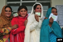 Pakistani voters pose with their national identity cards as they queue to cast their ballots at a polling station in Rawalpindi.