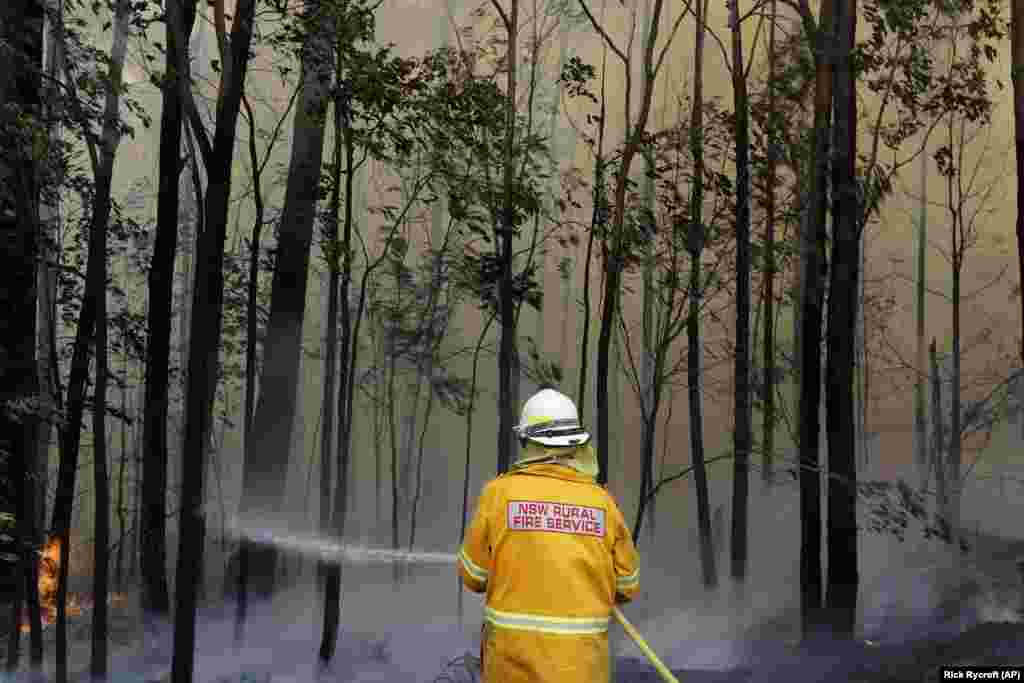 A firefighter manages a controlled burn near Tomerong, Australia, in an effort to contain a larger fire nearby. (AP/Rick Rycroft)