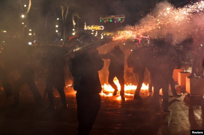 Një person duke hedhur fishekzjarrë gjatë protestës në Tiranë.