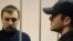 Mikhail Kosenko (left), one of the activists accused of violence at a rally on the eve of President Vladimir Putin's inauguration, stands in a defendant's cage in a court in Moscow in October 2013.