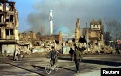 A 1994 photo shows Afghans walking past buildings in Kabul ruined in the country's civil war.