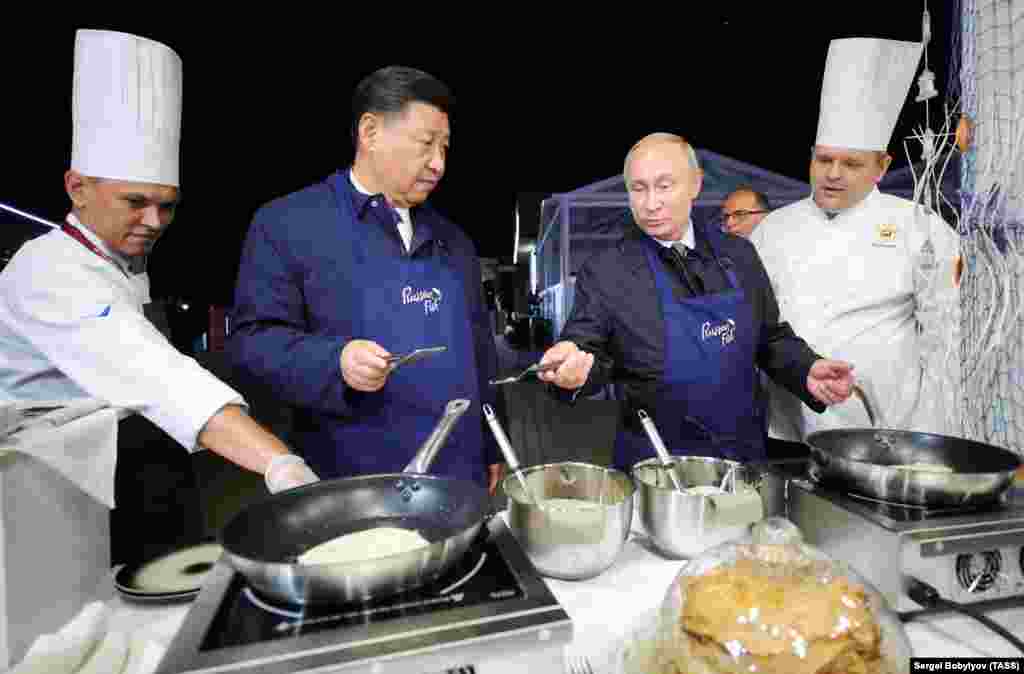 China&#39;s President Xi Jinping (second from left) and Russia&#39;s President Vladimir Putin (second from right) make bliny, or Russian pancakes, as they visit the Far East Street exhibition on the sidelines of the 2018 Eastern Economic Forum on Russky Island, near Vladivostok. (TASS/Sergei Bobylev)