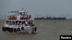 A ferry moves past the Jag Vasant, an LPG tanker arriving in Mumbai, India, on April 1 after transiting the Strait of Hormuz.