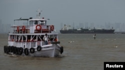 A ferry moves past the Jag Vasant, an LPG tanker arriving in Mumbai, India, on April 1 after transiting the Strait of Hormuz.