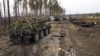 Ukrajinski vojnici prolaze na vrhu oklopnog vozila pored uništenih ruskih tenkova u predgrađu Kijeva, 31. marta 2022.