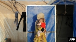An Iraqi woman carries a child at the Al-Khazir camp for internally displaced people.