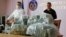 Klymenko's predecessor, Nazar Kholodnytskiy (left) leads a briefing next to $6 million in plastic bags in June 2020, two months before he resigned amid allegations that he helped officials suspected of corruption evade prosecution.