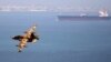 Iran -- An Iranian military fighter plane flies past an oil tanker during naval manoeuvres in the Persian Gulf and Sea of Oman, April 5, 2006