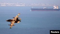 Iran -- An Iranian military fighter plane flies past an oil tanker during naval manoeuvres in the Persian Gulf and Sea of Oman, April 5, 2006