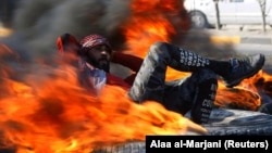 An Iraqi demonstrator sits amid burning tires blocking a road during anti-government protests in Najaf on February 2.