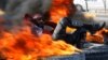 An Iraqi demonstrator sits amid burning tires blocking a road during anti-government protests in Najaf on February 2.