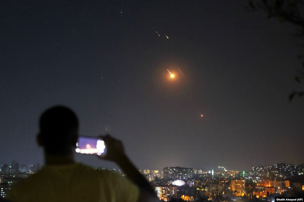 Një burrë duke shkrepur një fotografi me telefon mobil, teksa raketat e lëshuara nga Irani fluturonin drejt Izraelit mbi territorin sirian, në Damask, më 18 qershor.