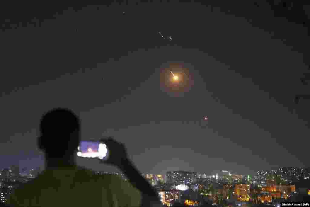 Një burrë duke shkrepur një fotografi me telefon mobil, teksa raketat e lëshuara nga Irani fluturonin drejt Izraelit mbi territorin sirian, në Damask, më 18 qershor.