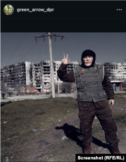 Zlatko Novković sa podignuta tri prsta pozira ispred zgrada razorenim u ruskim udarima na ukrajinski grad Mauripolju (Instagram post iz 2022. godine)